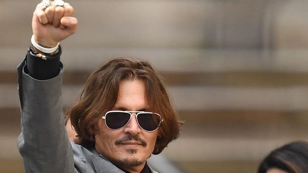 Johnny Depp levanta una mano de victoria al salir del juicio