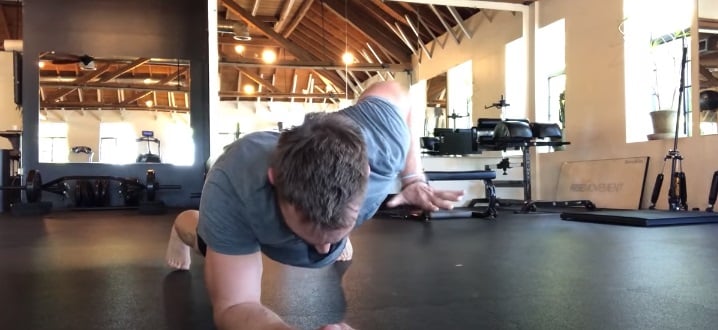 Entrenador de Brie haciendo plancha con un solo brazo
