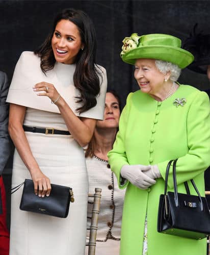 Meghan Markle con un vestido con capa corta de Givenchy en compañía de la reina Isabel II