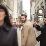 Hombre y mujer con atuendos elegantes en una vibrante calle de la ciudad, expresando sorpresa.