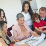 Una familia discute los planes de propiedad con un agente inmobiliario en interiores, enfocándose en la compra de una nueva casa.
